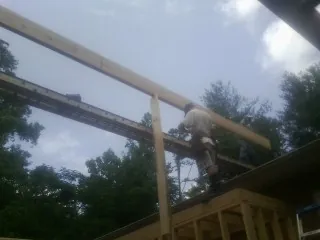 Carpenter setting a ridge beam over a new addition frame — Ice Dam Removal by Roofing Brothers in Pittsville