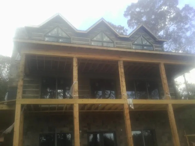 Dormers and porch framing on a large log home under construction — Roof Coating work by our crew in Pittsville