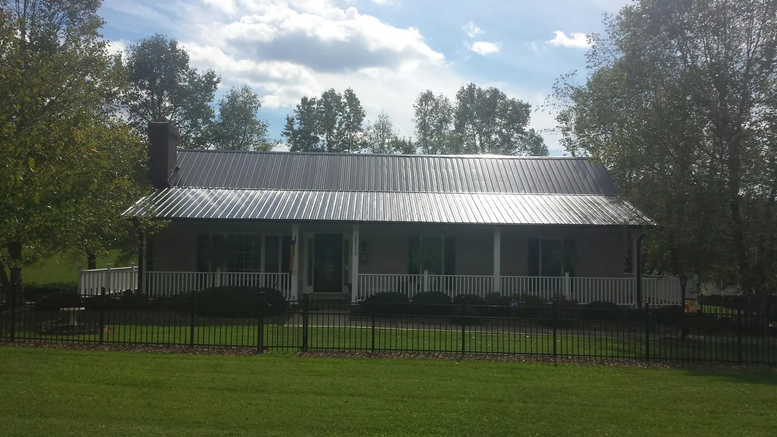 Gray metal roof on a brick ranch with a full width front porch — Gutter Guard Installation work by our crew in Pittsville