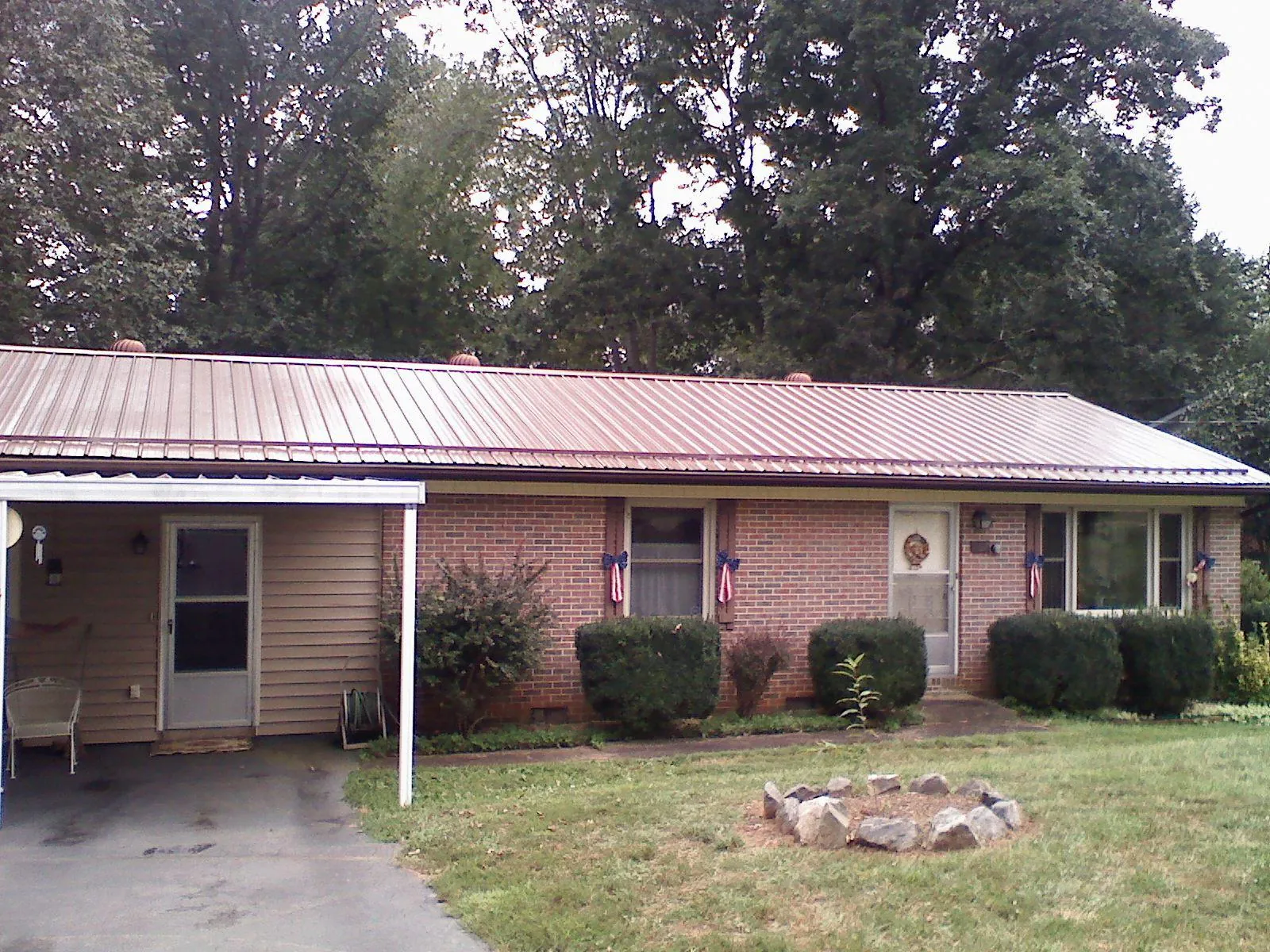 Bronze metal roof and carport on a brick ranch home — Roof Repair work by our crew in Pittsville