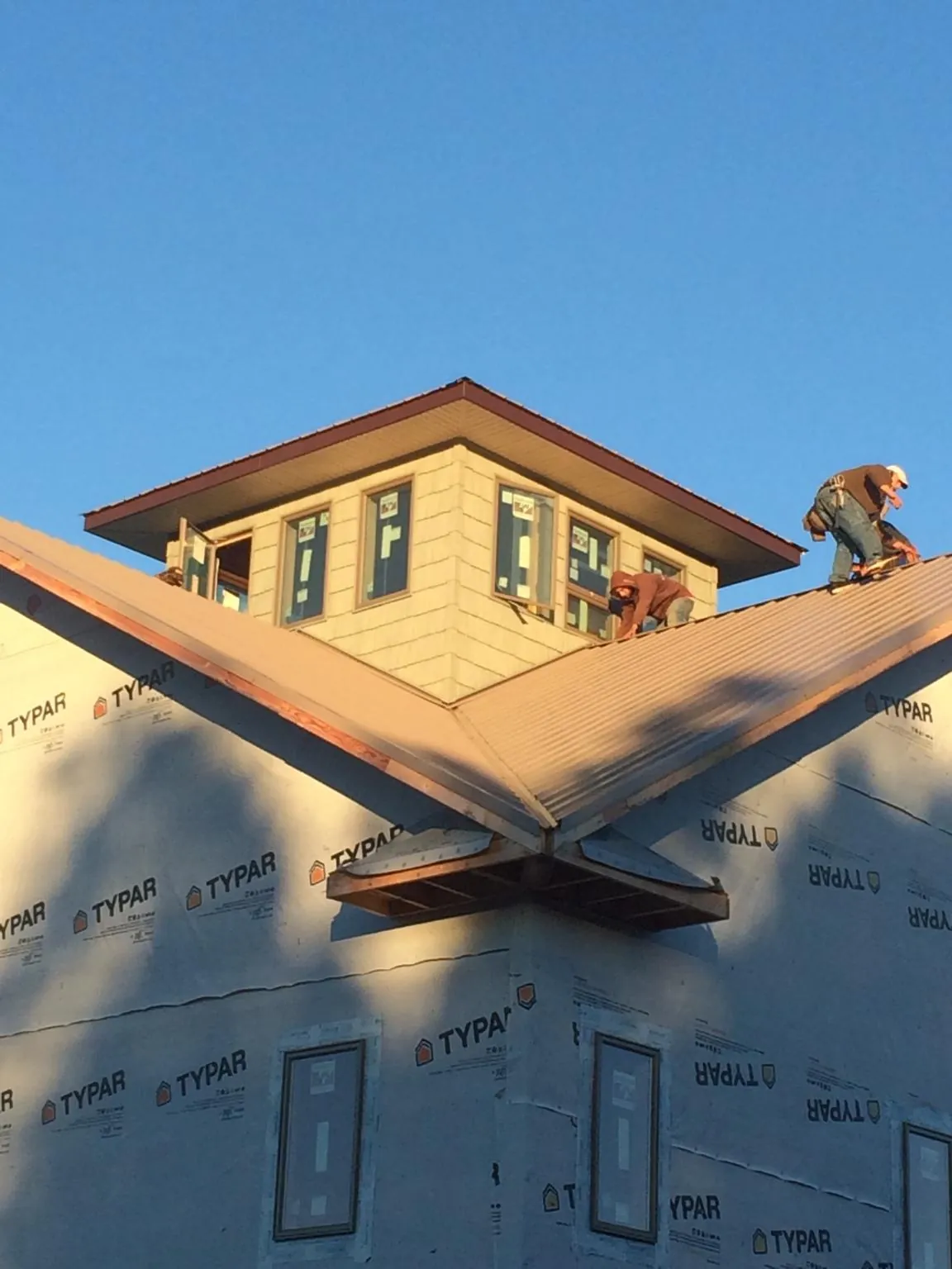 Roofers working around a rooftop cupola on a new metal roof at sunset — Roof Waterproofing in Pittsville by Roofing Brothers